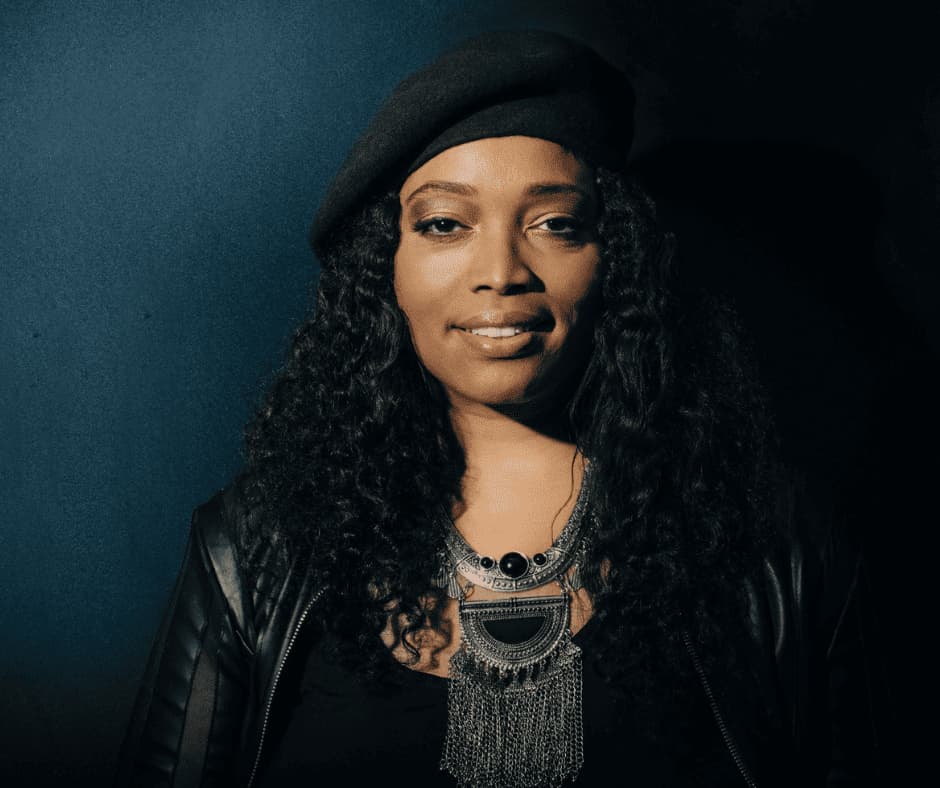 Woman wearing black beret, leather jacket, and ornate metal necklace.