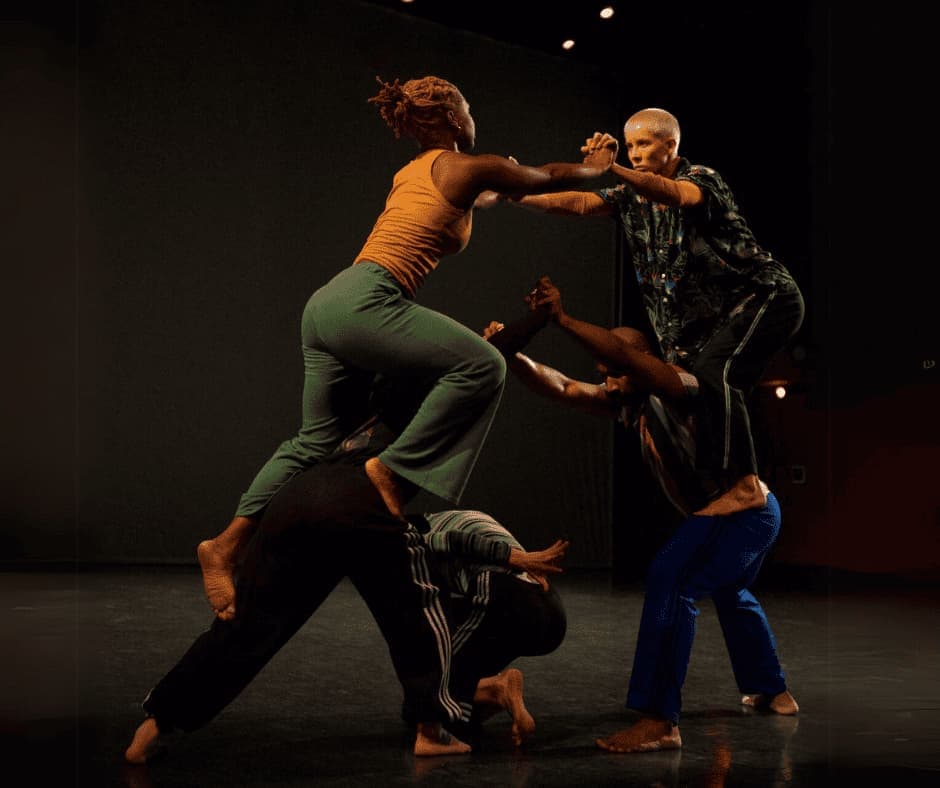 Five dancers, one each on the back of another and one on the floor.