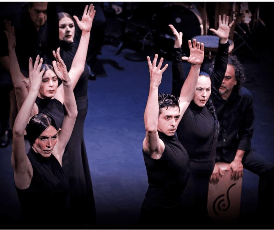 Group of flamenco dancers with their hands in the air