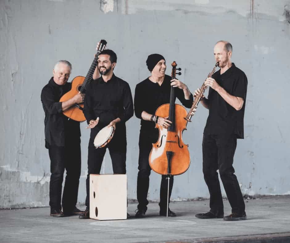 Four musicians in all black playing a guitar, a tambourine, a cello and a clarinet.