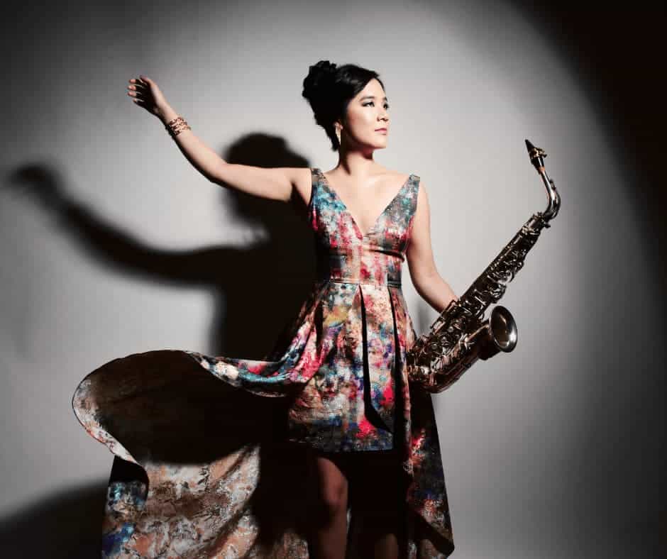 A woman in a colorful dress holding a saxophone