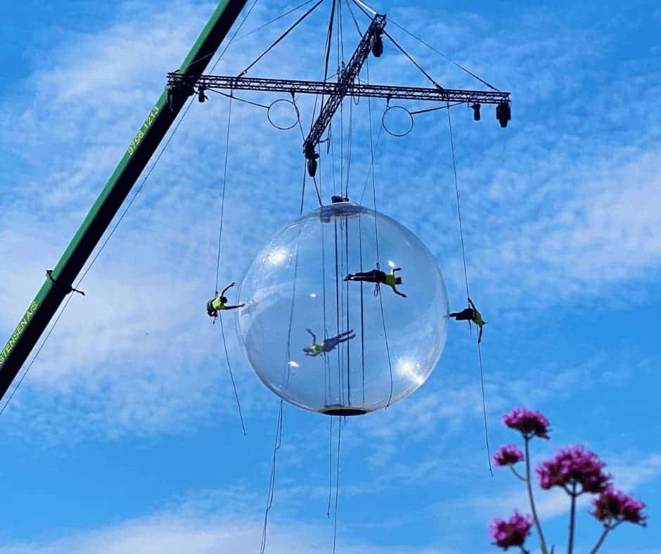 Four people and a giant bubble hanging off a crane