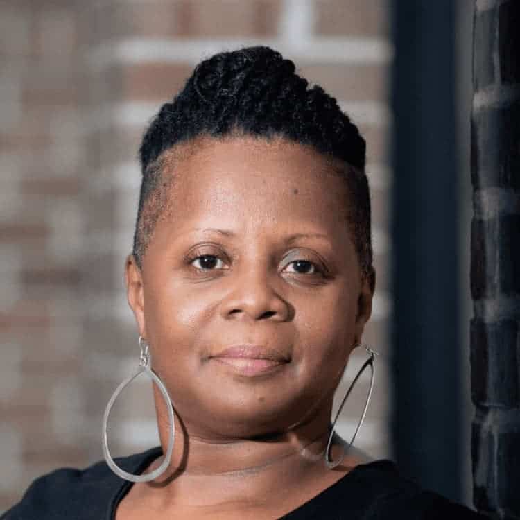 Black woman wearing silver hoop earring smiling at the camera