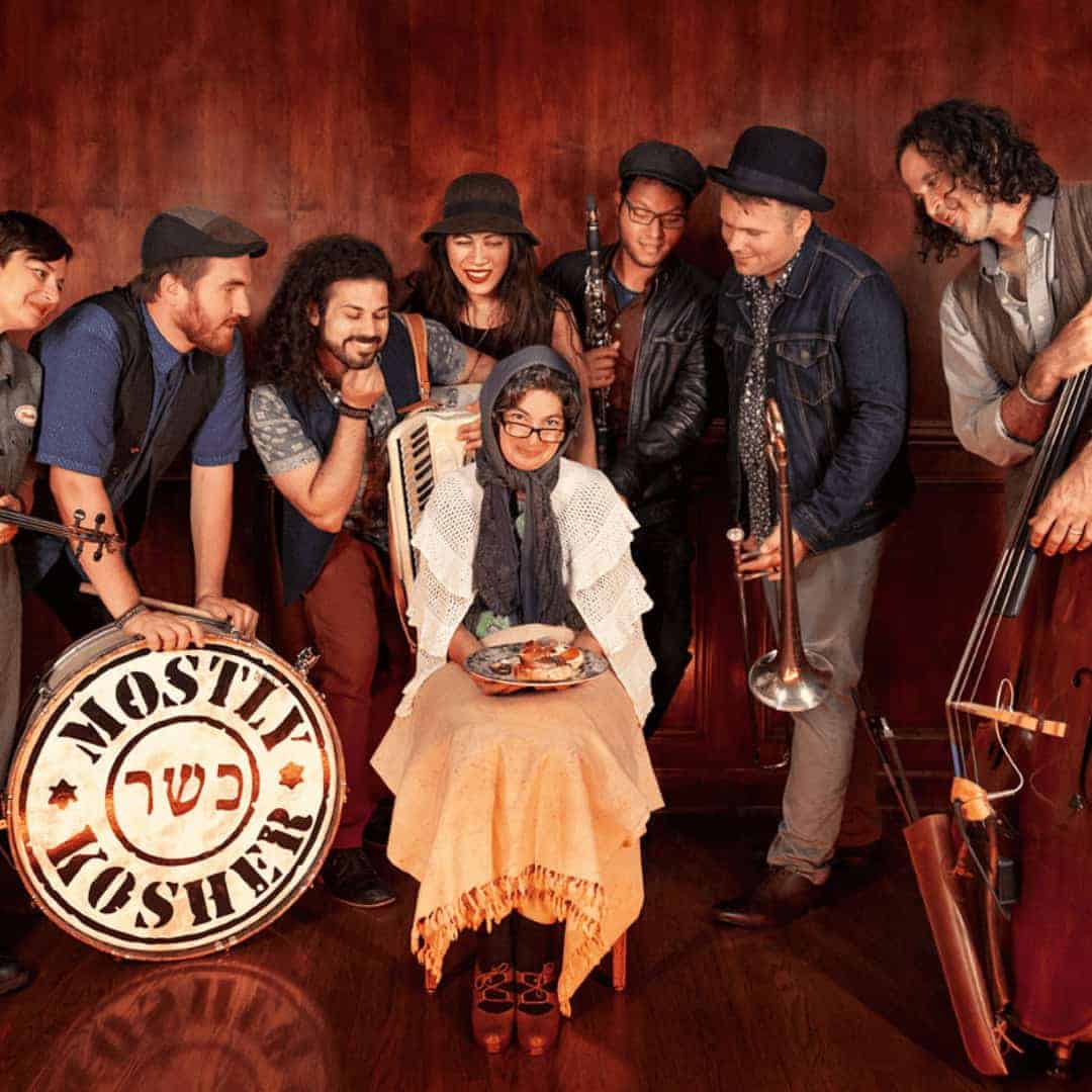 Group of individuals holding instruments in front of burgundy backdrop