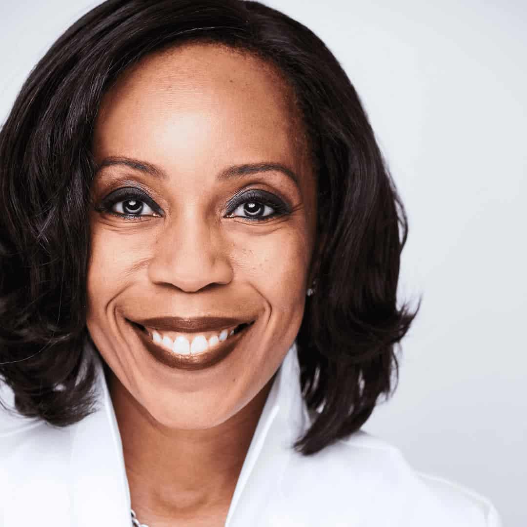 Headshot of Renae - brown skin tone, with dark brown shoulder-length hair and a white shirt; photo by Cathryn Farnsworth.